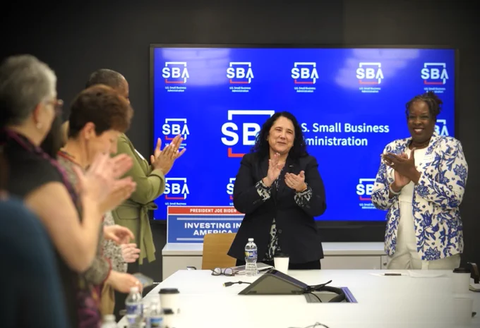 Administrator Guzman and several others stand and clap during a meeting.