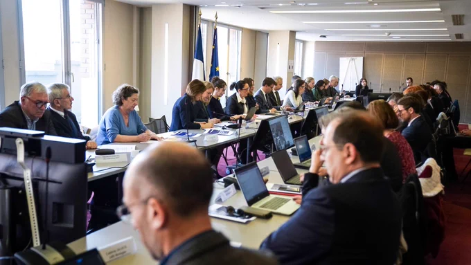 Photographie prise lors de la présentation de la stratégie de lutte contre la maltraitance. 
Les différents acteurs sont réunis autour d’une grande table de réunion. 

Fadila Khattabi se trouve au milieu de cette table à gauche de l’image. Derrière elle sont installés un drapeau français et un drapeau européen.