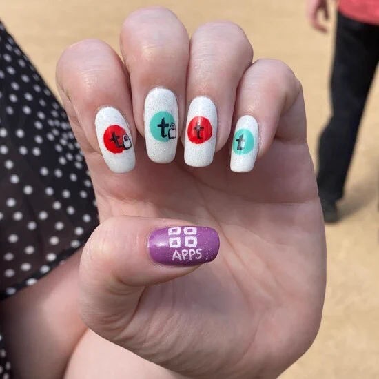 Photograph of Tessitura member’s manicure featuring different Tessitura logos on each nail.