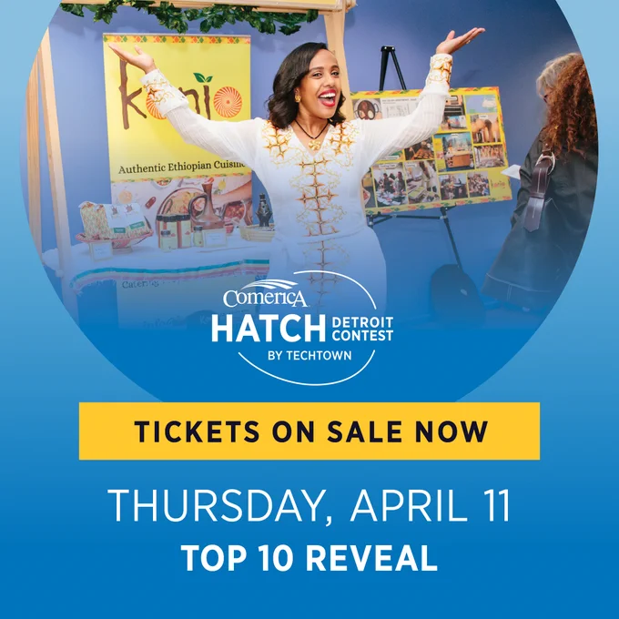 A graphic featuring an image of a woman smiling and posing in front of a pop-up display for her business, Konjo Me. Overlapping this photo is the Comerica Hatch Detroit Contest by TechTown logo, followed by the text "Tickets on sale now Thursday, April 11 Top 10 Reveal"