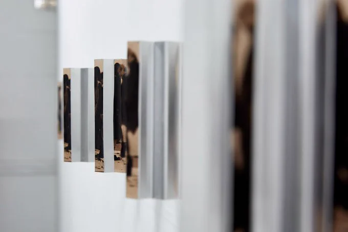 Wall-mounted artwork by Shutong Li, repeating images of standing figures, receding into the distance. 

