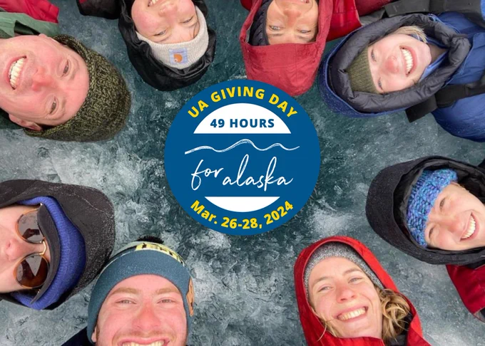 Eight Arctic researchers laying on lake ice in a circle with the UA Giving Day logo in the center