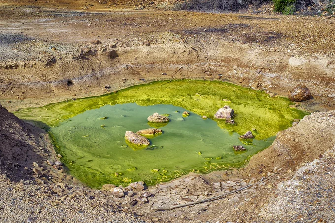 A green pool of water in a hole in the ground
