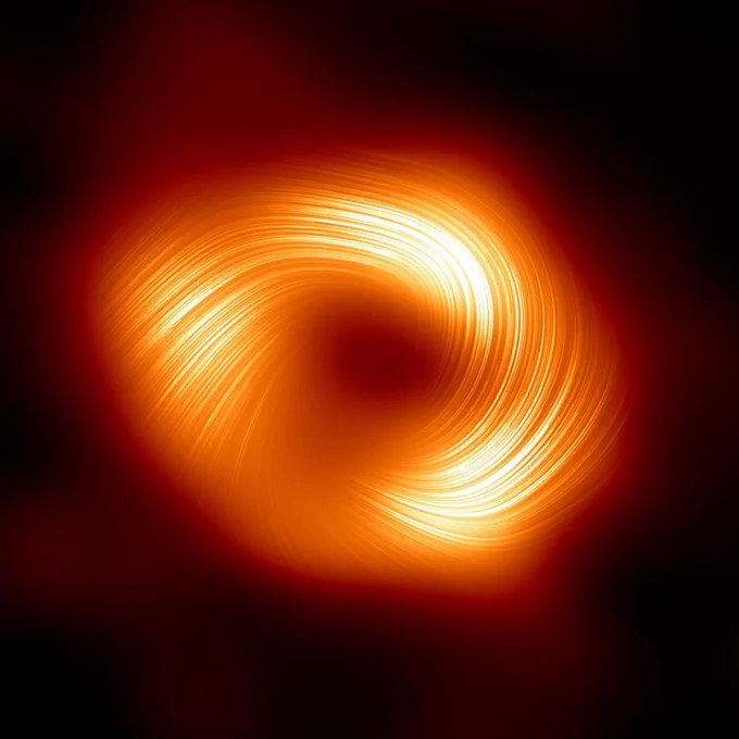 An image of the black hole at the center of the Milky Way, Sagittarius A*, which appears as an orange donut shape with a dark center. At the edges of the black hole are fine lines.