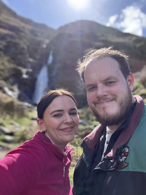 Matt and Jo, smiling in front of a waterfall