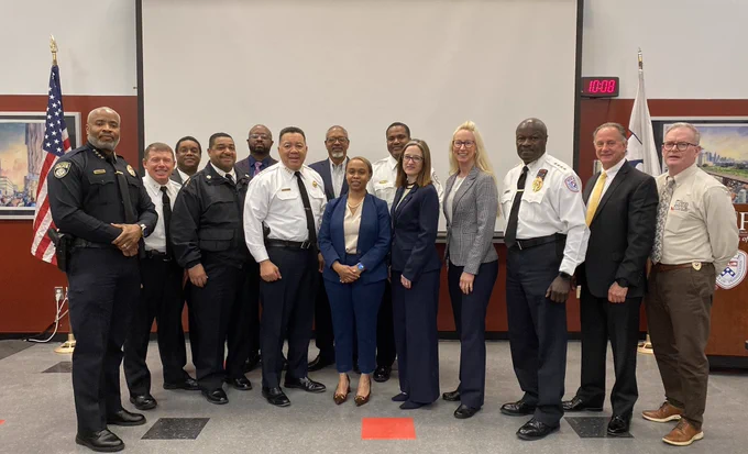 Photo of a group of 14 people, many in police uniform, standing in a seminar room.