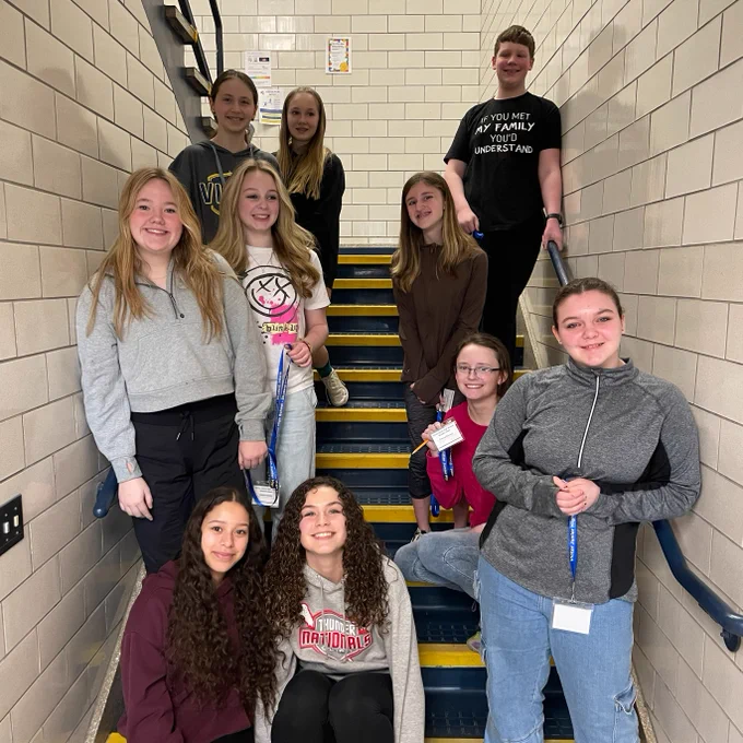 Smiling students standing in a stairwell.