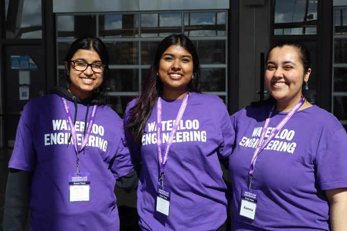 Photo of three Waterloo Engineering March Open House volunteers wearing purple t-shirts and smiling at the camera.