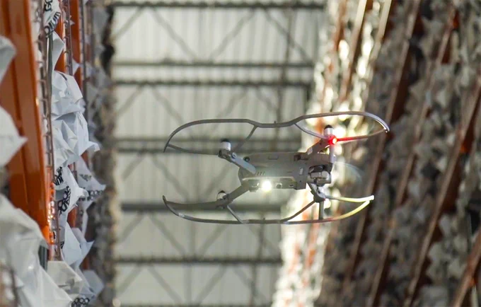 Looking up at a drone flying inside a warehouse.