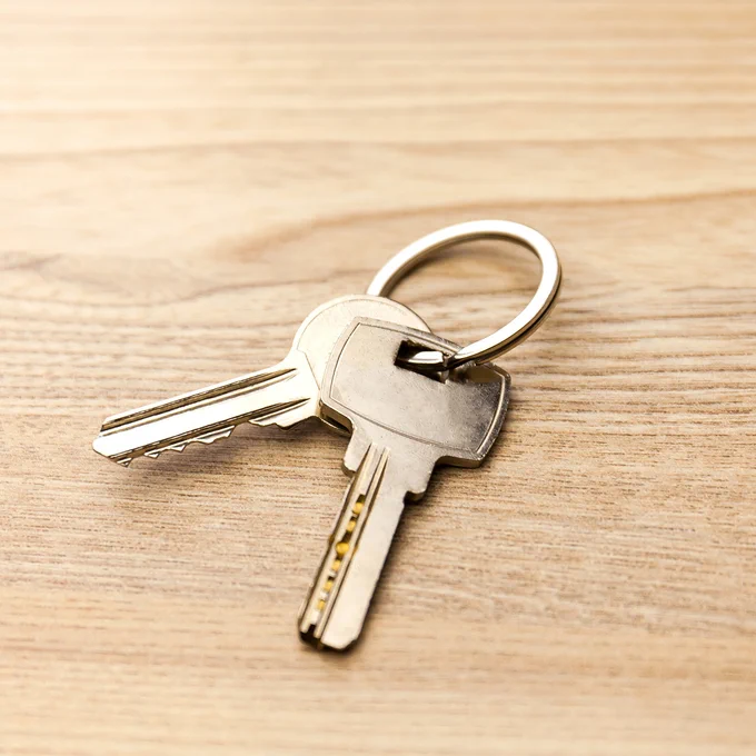 The image depicts a set of keys on a wooden table.