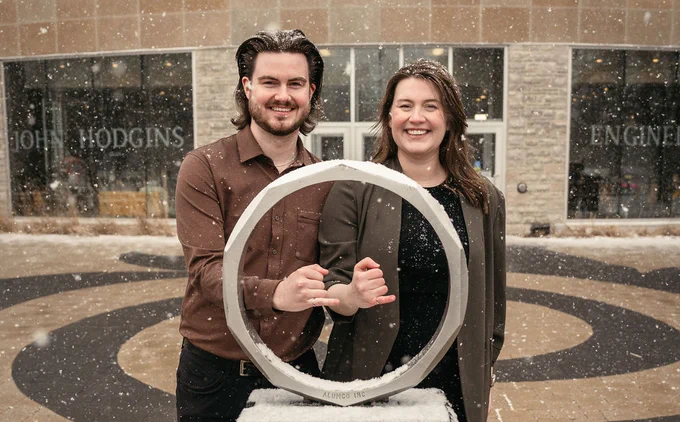 Jarod and Ashton hold out their pinky fingers with Iron Rings in the Iron Ring Statue
