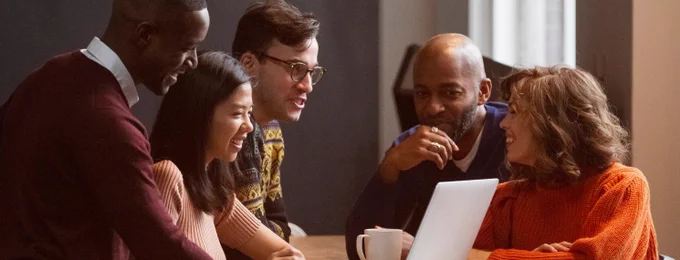 Stock image of people discussing something over coffee in front of a laptop screen