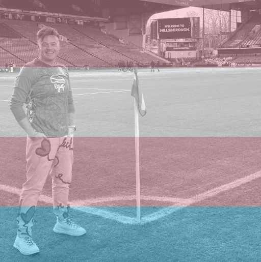 A photo with a filter in trans colours of Rainbow Owls member Sam Elliott-Olechnowicz.

He is wearing a Sheffield Wednesday shirt and standing next to a Rainbow Laces flag at Hillsborough Stadium.