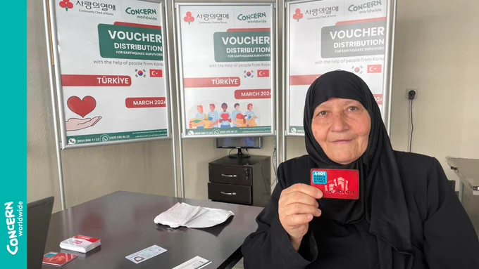 Older lady posing for the camera holding a market card