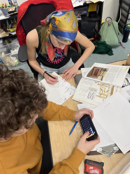 Two students calculating new dimensions for lumber for our custom workbench.