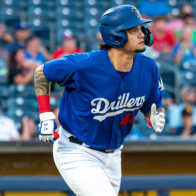 Tulsa Drillers outfielder Andy Pages looks off into the distance during game action while running the bases. He wears a blue uniform top, blue batting helmet and white pants.