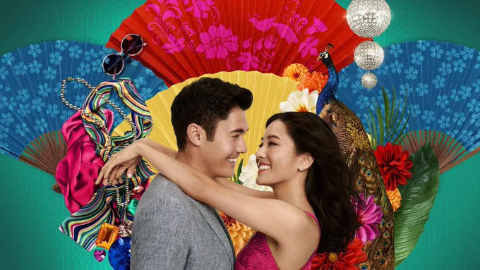 Constance Wu and the handsome love interest from Crazy Rich Asians smile and embrace in front of colourful fans