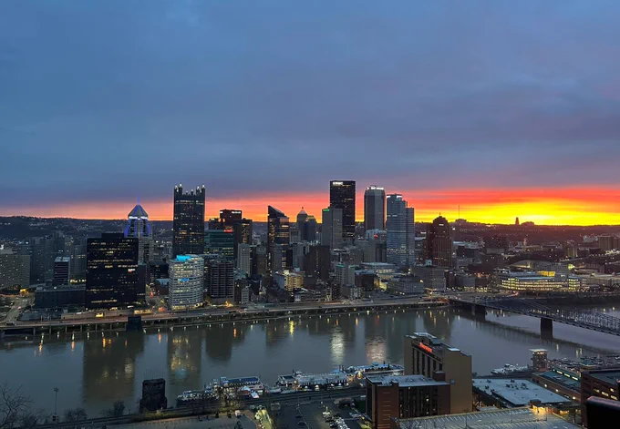 Sunrise behind a skyline photo of buildings with lights.