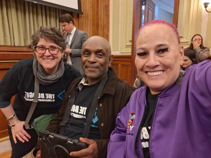 A photo of three smiling people as they sit in on the mayor's budget proposal on April 3.