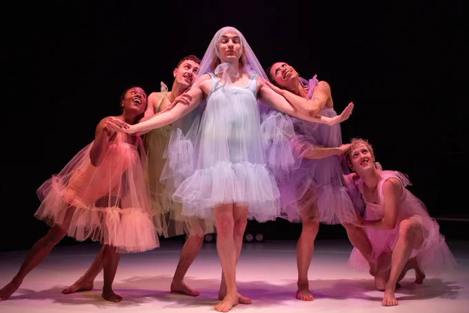 Jack Sears wearing a mesh dress and veil with four dancers leaning against him in a triangular formation