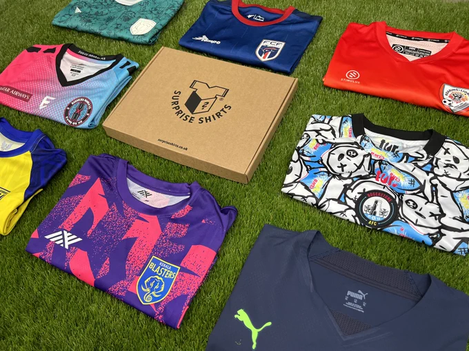 8 Surprise Shirts around a Surprise Shirts box; FC Prishtina, Cape Verde, Roaring Lions, Maharlika Manila, AFC Rogerstone, FC Korriku, Kerala Blasters & Greuther Furth.