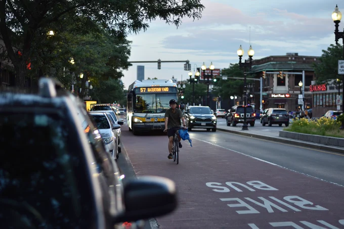 A photo of the 57 bus and cyclist using the bus and bike lane together.