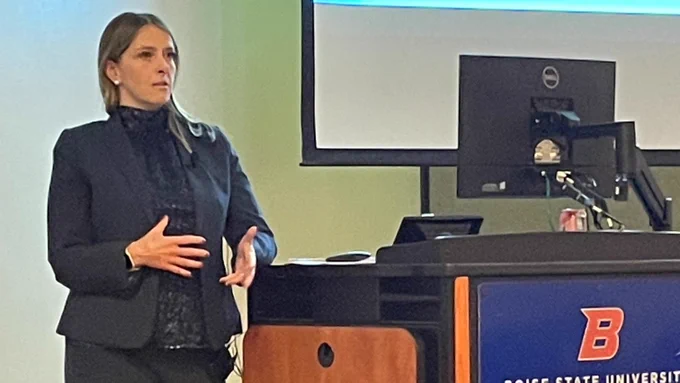 AUSA Kassandra McGrady stands next to a podium presenting during BSU's Victims' Rights Week workshop on the topic of stalking. The podium displays an orange "B" and reads Boise State University.