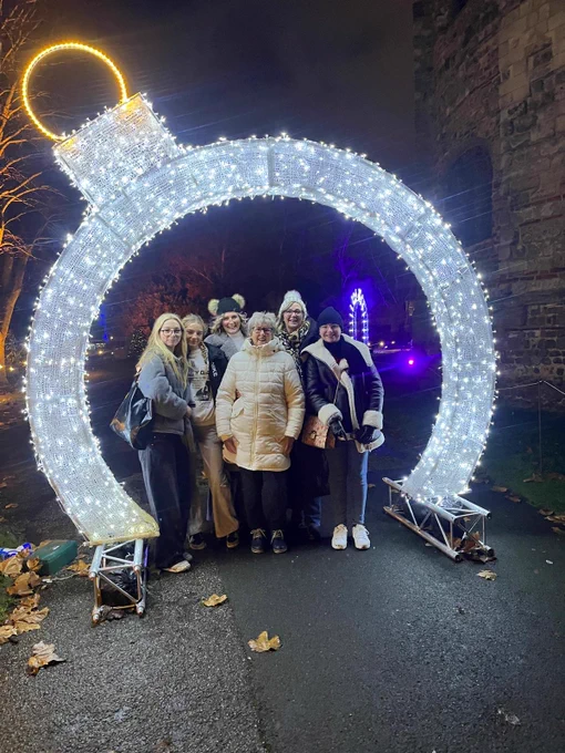 Group of people outside standing under huge lit-up Christmas bauble