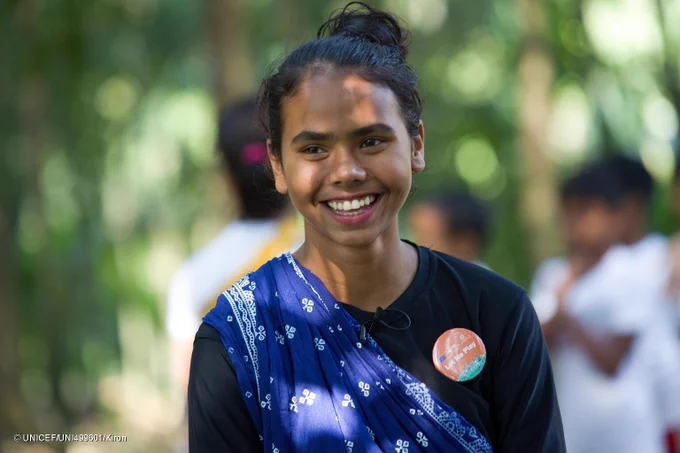 Mim smiles as she conducts a warm-up session for children.