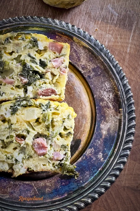 Close-up of eggs Florentine Ham & Cheese cups, cut in half on a tarnished silver plate revealing the ingredients for egg, ham, spinach and cheese. 