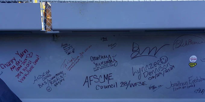A steel beam covered in signatures. 