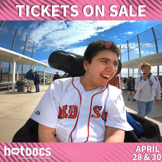Samuel smiling in his wheelchair wearing a Red Sox jersey at a baseball game. A pink border is above and below the image with white text that reads "Tickets on sale. April 28 & 30" and the HotDocs logo.