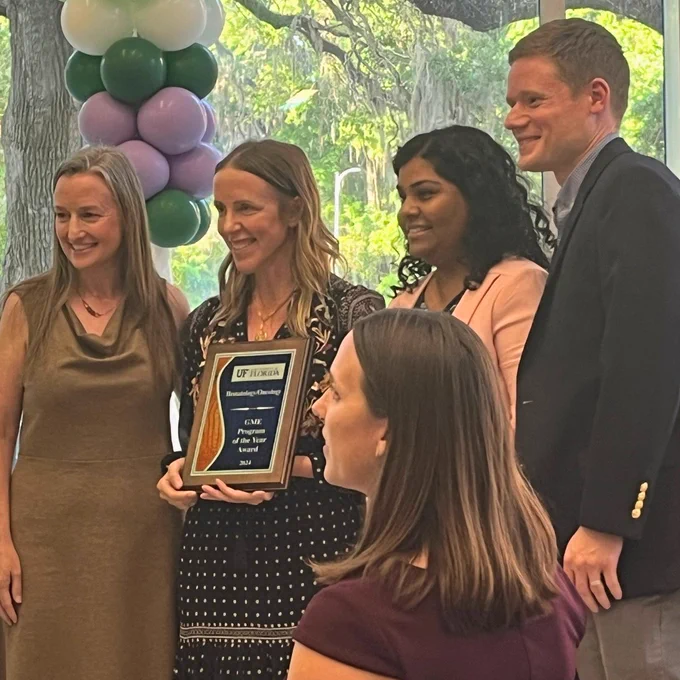 Dr. Murphy holds the award plaque while surrounded by her team during the ceremony.