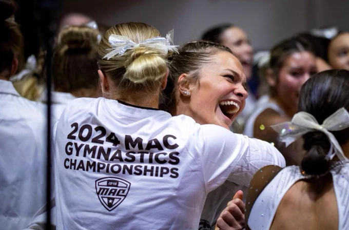 Two WMU gymnasts ecstatically hugging after they won the 2024 MAC championship tournament. 