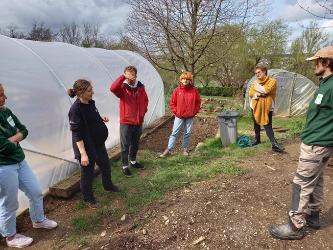 People from the Green Communities team and Devon Wildlife Trust standing outside, next to a polytunnel talking.