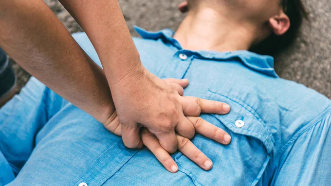 This image depicts a person performing CPR on another person.