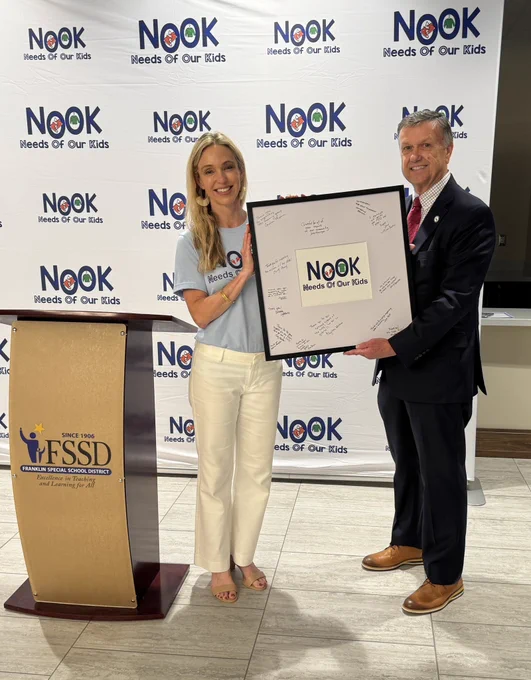 A woman holding a framed award along with a man in a suit.