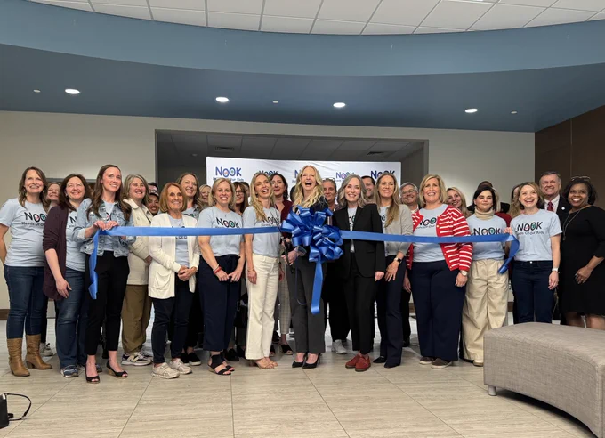 Large group standing behind a large blue ribbon