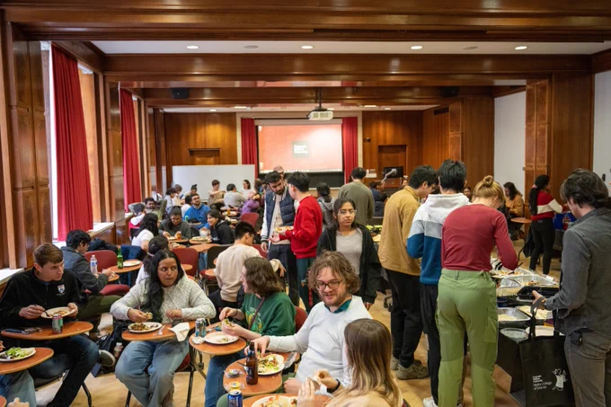 A large group of students sits together eating food.