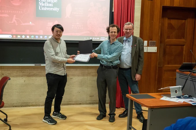 A student is given an award by his advisor and Interim Dean Curtis Meyer.