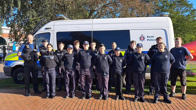 A line up of cadets in front of a police van. 