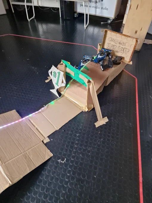 An image of the starting point of the cardboard track which says "CARDBOARD MARIO KART". A toy car is just about to start the game.
