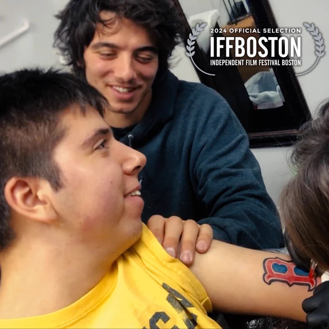 Samuel getting the Boston Red Sox logo tattooed on his arm with his brother Isaiah sitting beside him. In the top right corner is a white laurel that reads “2024 Official Selection IFFBOSTON Independent Film Festival Boston”