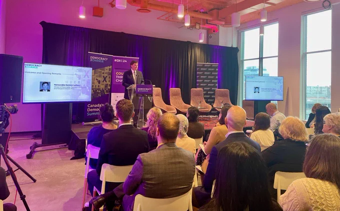 Minister LeBlanc standing at a podium speaking at the Democracy XChange Summit.