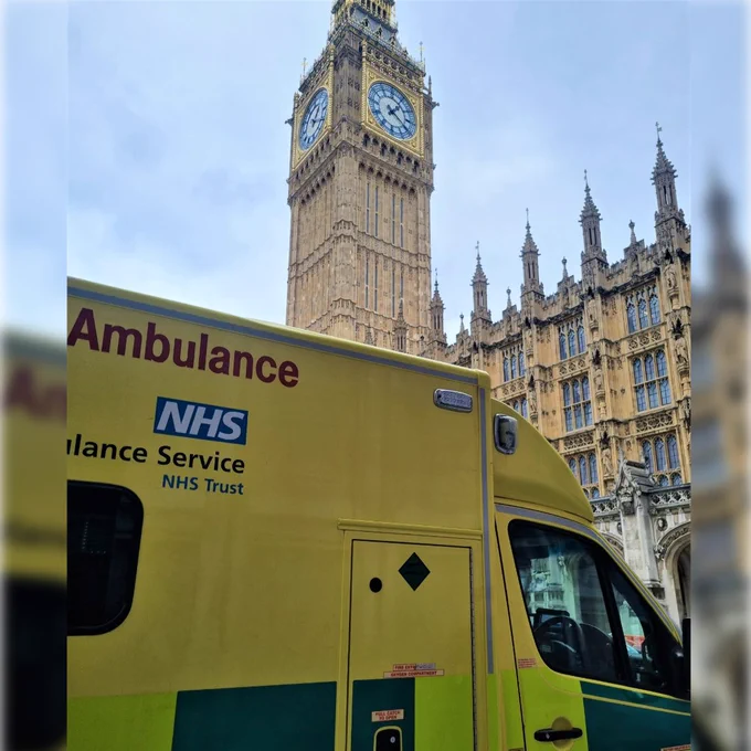 Image shows an ambulance driving past Big Ben, with the Palace of Westminster visible in the background. 