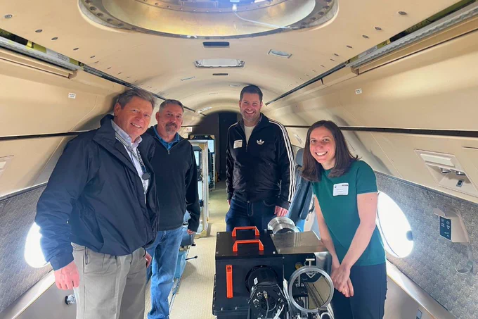 A group of researchers stand in the NSF NCAR Gulfstream V fitted with the ACES instrument that will look at the sun's corona during the eclipse.