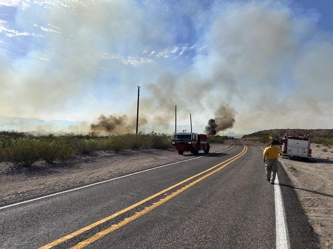 Firefighters survey the fire and watch for spots across the road