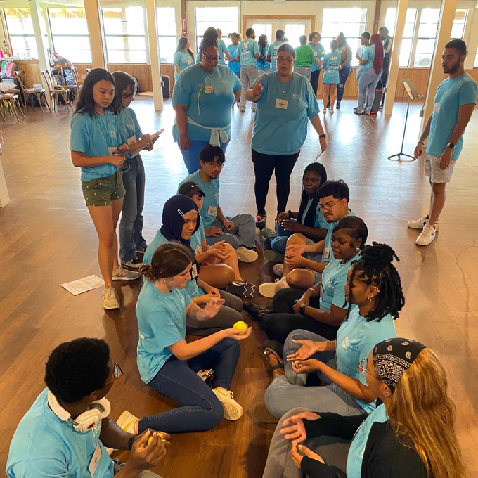 students sit on the floor and participate in an activity