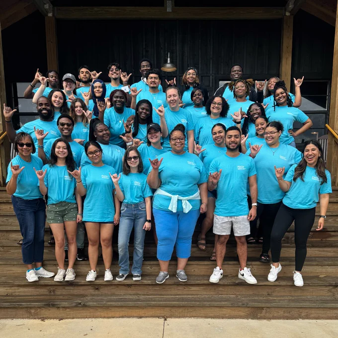 students take a group photo in matching blue shirts