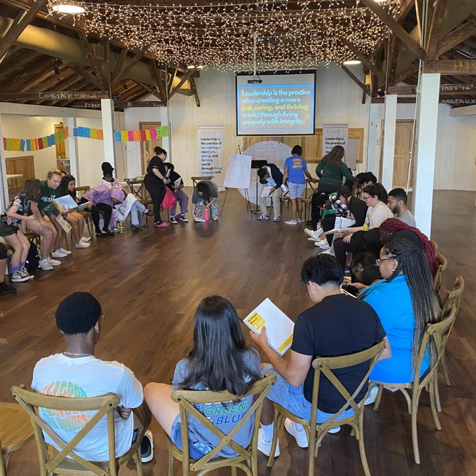 students sit in chairs in a circle and participate in an activity